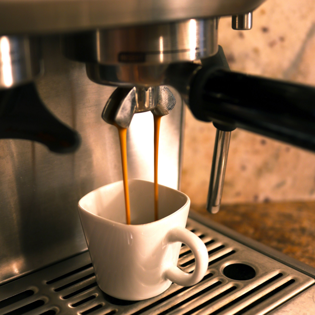 Café cayendo en una taza desde la salida de una cafetera