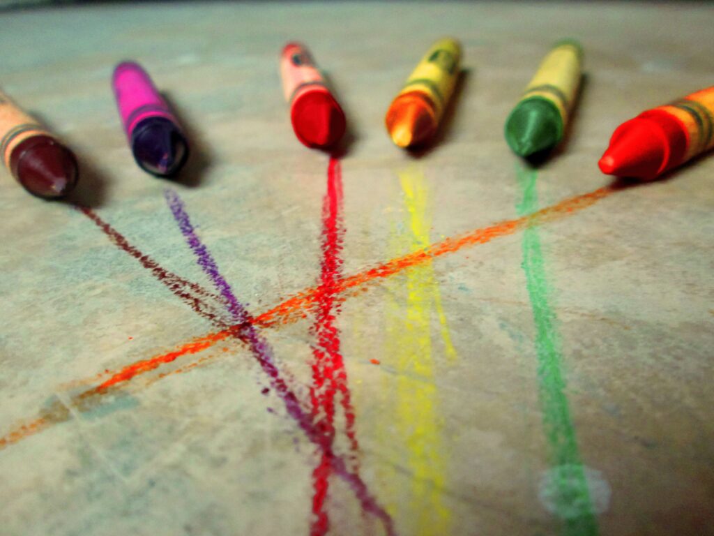 Ceras de colores junto a los trazos que acaban de dejar sobre una superficie clara