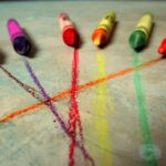 Ceras de colores junto a los trazos que acaban de dejar sobre una superficie clara