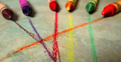 Ceras de colores junto a los trazos que acaban de dejar sobre una superficie clara