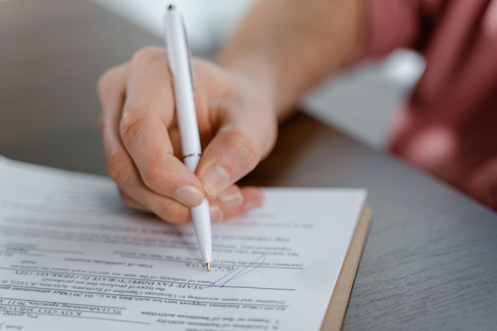 Mano firmando un contrato de alquiler sobre una mesa