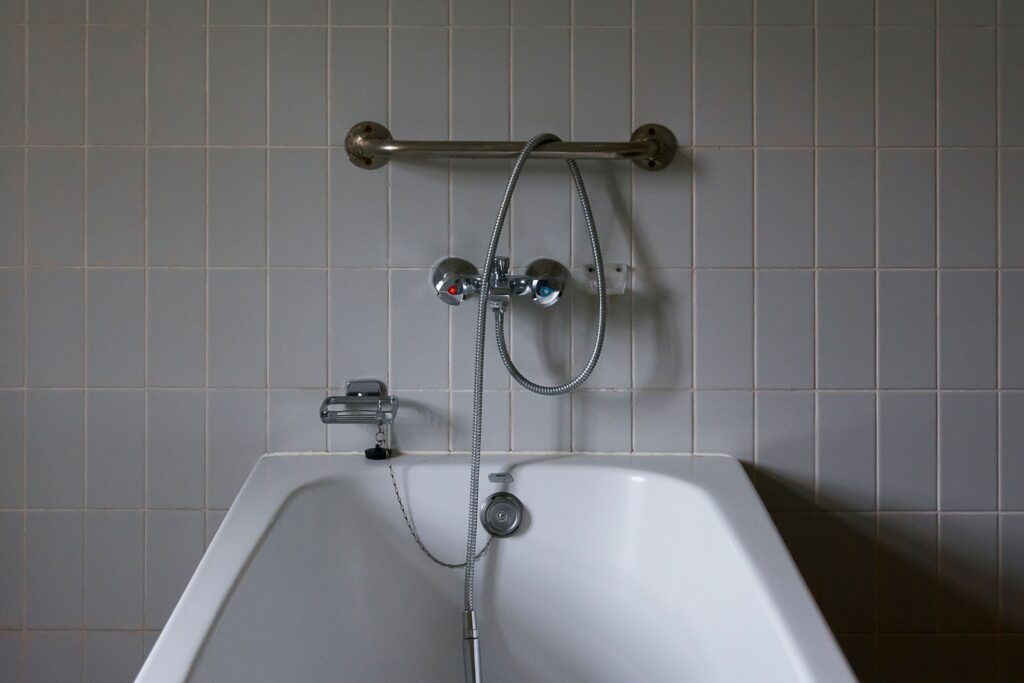 Junta de silicona entre una bañera blanca y la pared alicatada