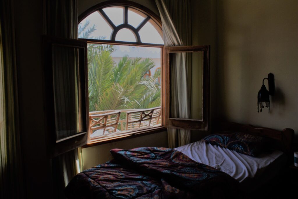 Ventana abierta en un dormitorio con la cama destapada