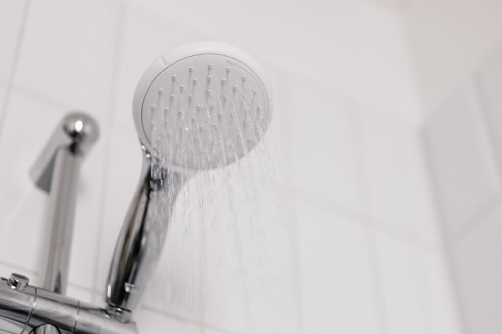 Alcachofa de ducha cromada en un baño de azulejo blanco
