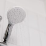 Alcachofa de ducha cromada en un baño de azulejo blanco