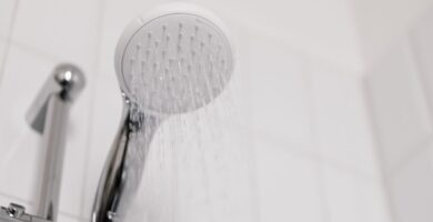 Alcachofa de ducha cromada en un baño de azulejo blanco